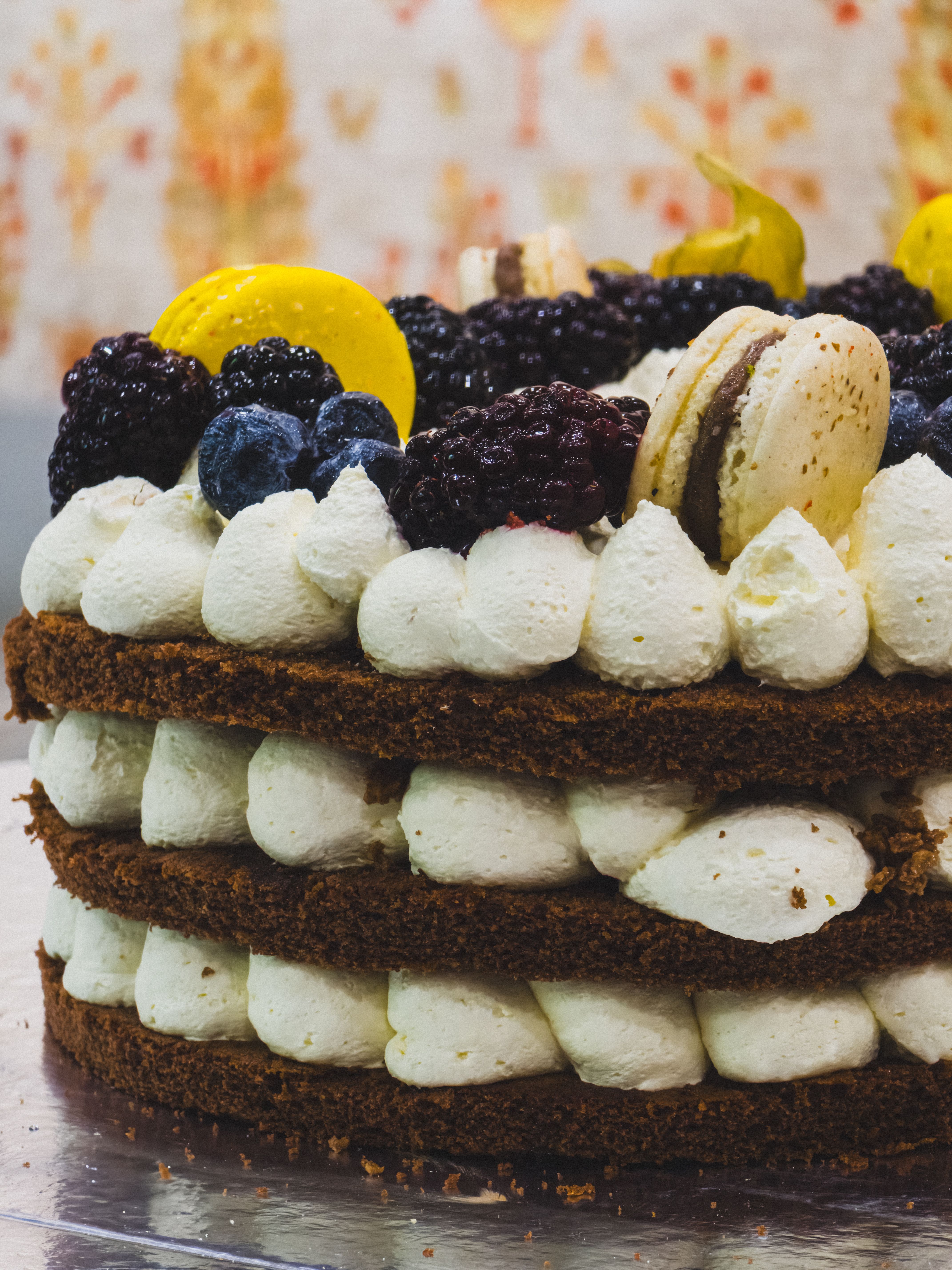 Delicious layered cake adorned with creamy frosting, mixed berries, and macarons.