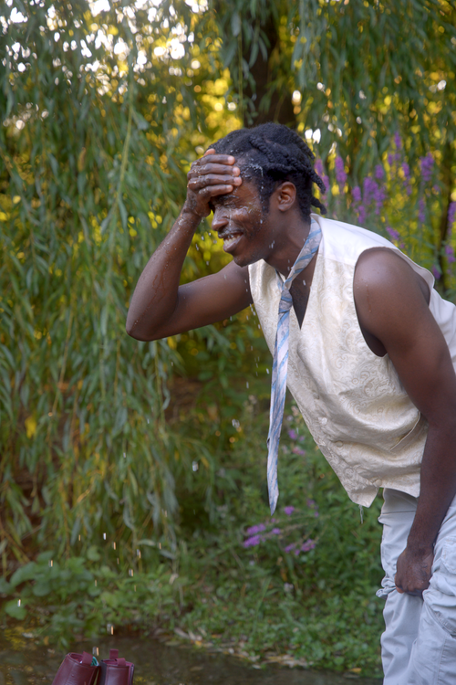 Free A joyful adult splashes water on face outdoors in a lush green park. Stock Photo