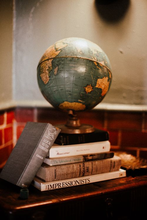Free A vintage globe sits atop a stack of books, creating a warm and intellectual ambiance. Stock Photo