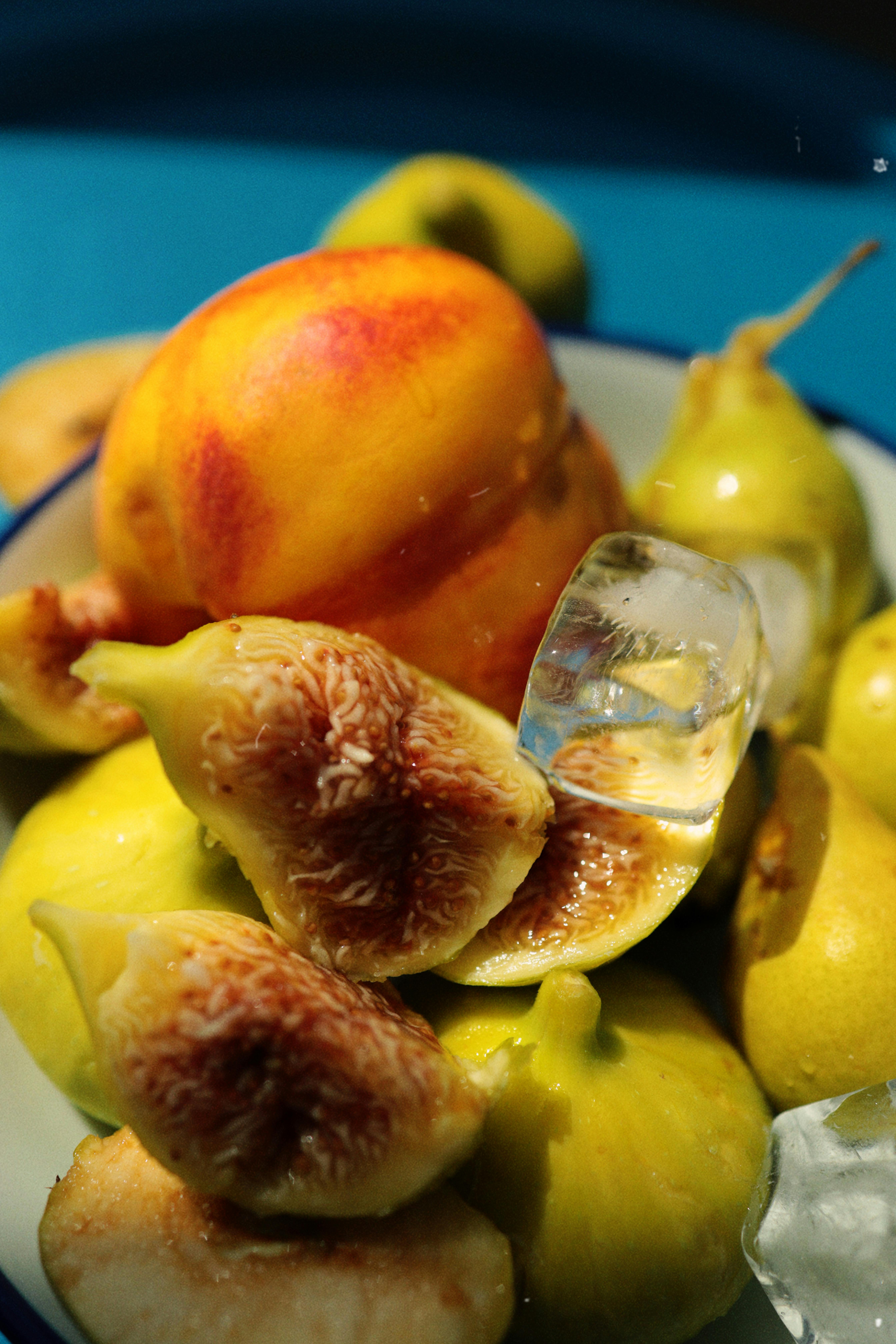 Delicious ripe figs and nectarines with ice cubes on a blue background.
