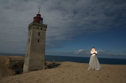 Женщина, стоящая возле серого маяка