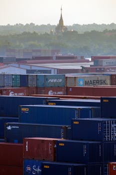 Vibrant shipping containers with a distant golden temple in a misty backdrop.