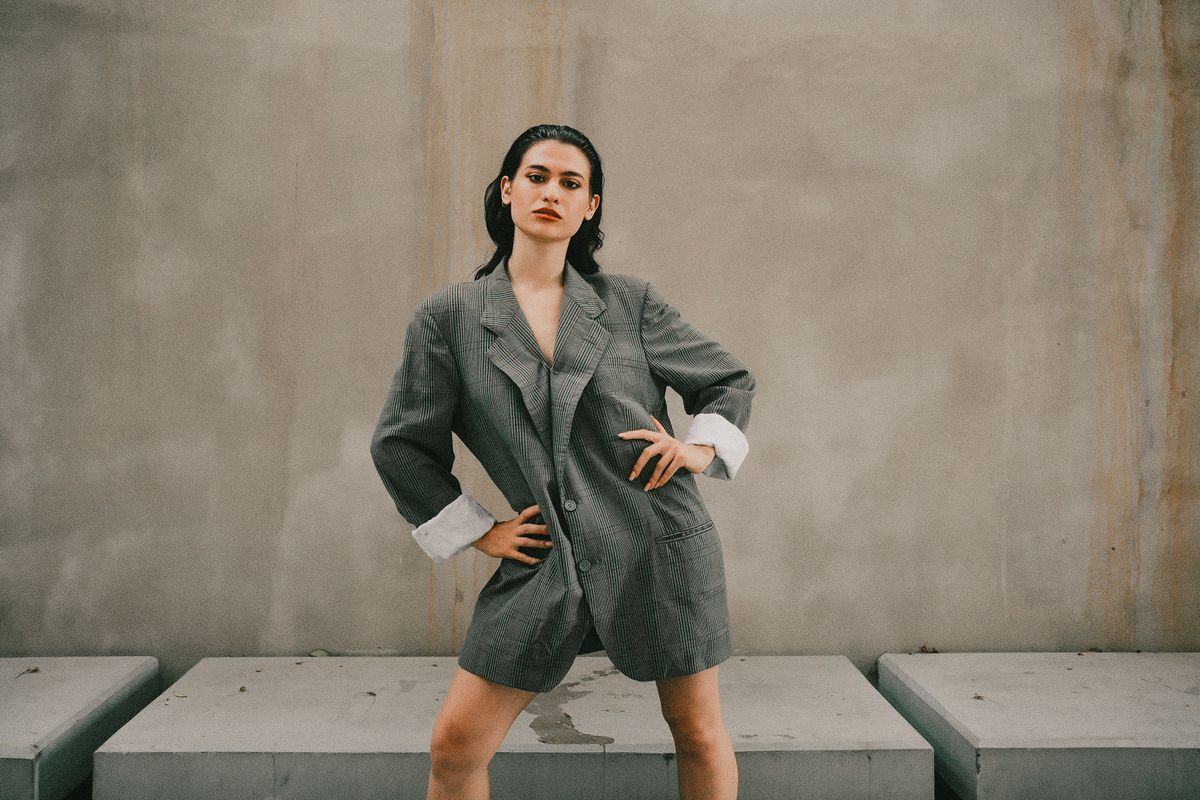 Model in an oversized grey checked blazer against a concrete wall — photo by Mert Coşkun on Pexels