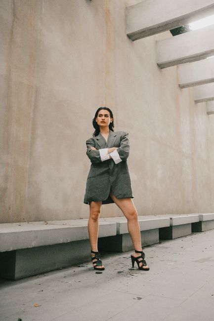 Confident woman posing in an oversized blazer in a minimalist urban environment.