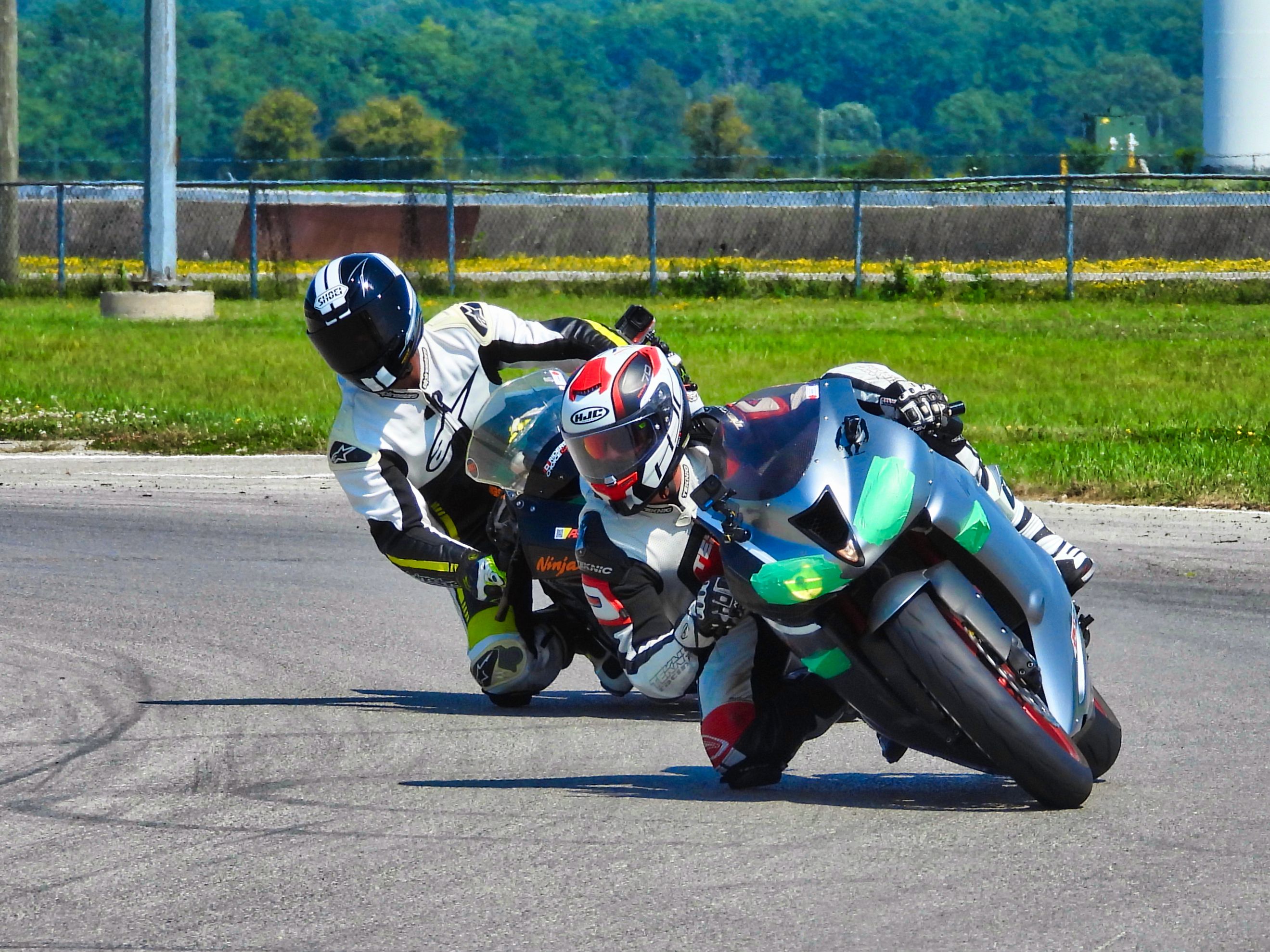 Two motorcyclists racing on a track, showcasing speed and precision in Cayuga, Ontario.