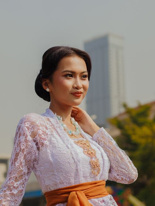 Free Young woman in traditional attire poses outdoors with a cityscape backdrop, showcasing cultural elegance. Stock Photo