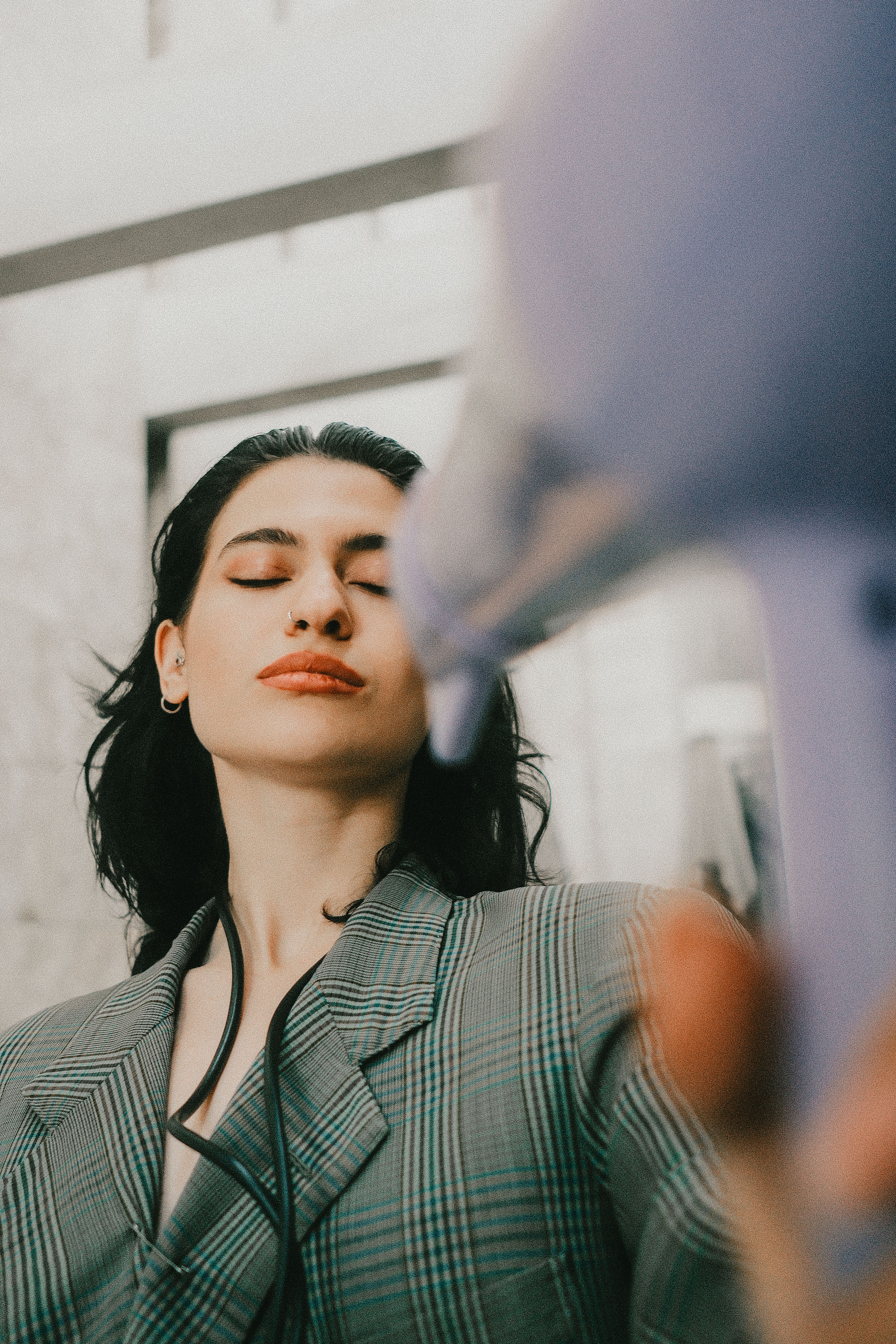 Close-up of a woman using a hair dryer in a modern bathroom setting.