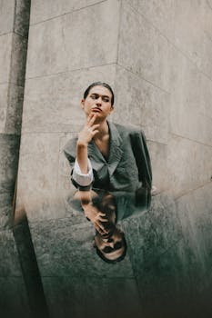 Artistic portrait of an adult in a blazer reflected on a marble surface.
