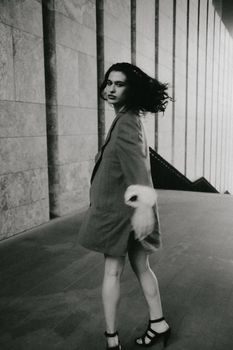 Artistic black and white photo of a woman in motion with cityscape backdrop.