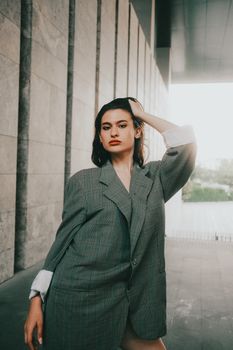 Stylish woman in plaid blazer posing confidently in an urban setting.