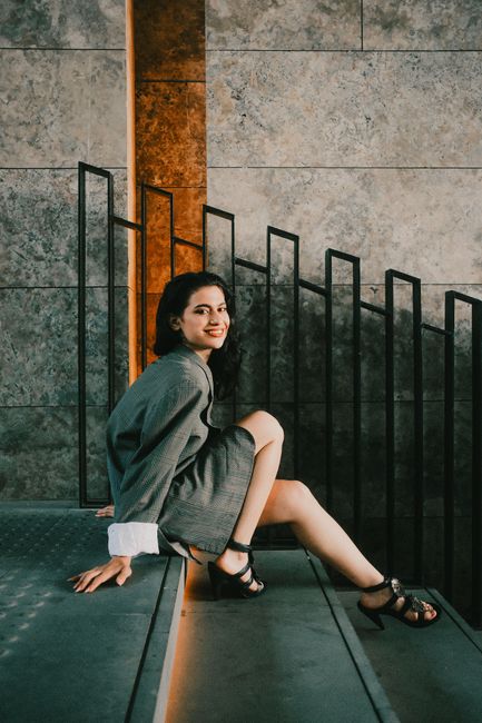 A fashionable woman sitting on a chic staircase with a modern design indoors.