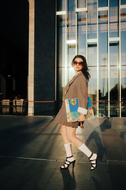 Stylish woman carrying an art portfolio outdoors, reflecting urban fashion.