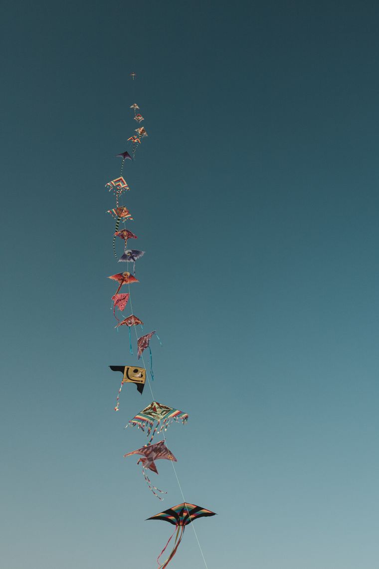 A long string of kites climbing a clear blue sky — photo by Lorenc Memaga on Pexels
