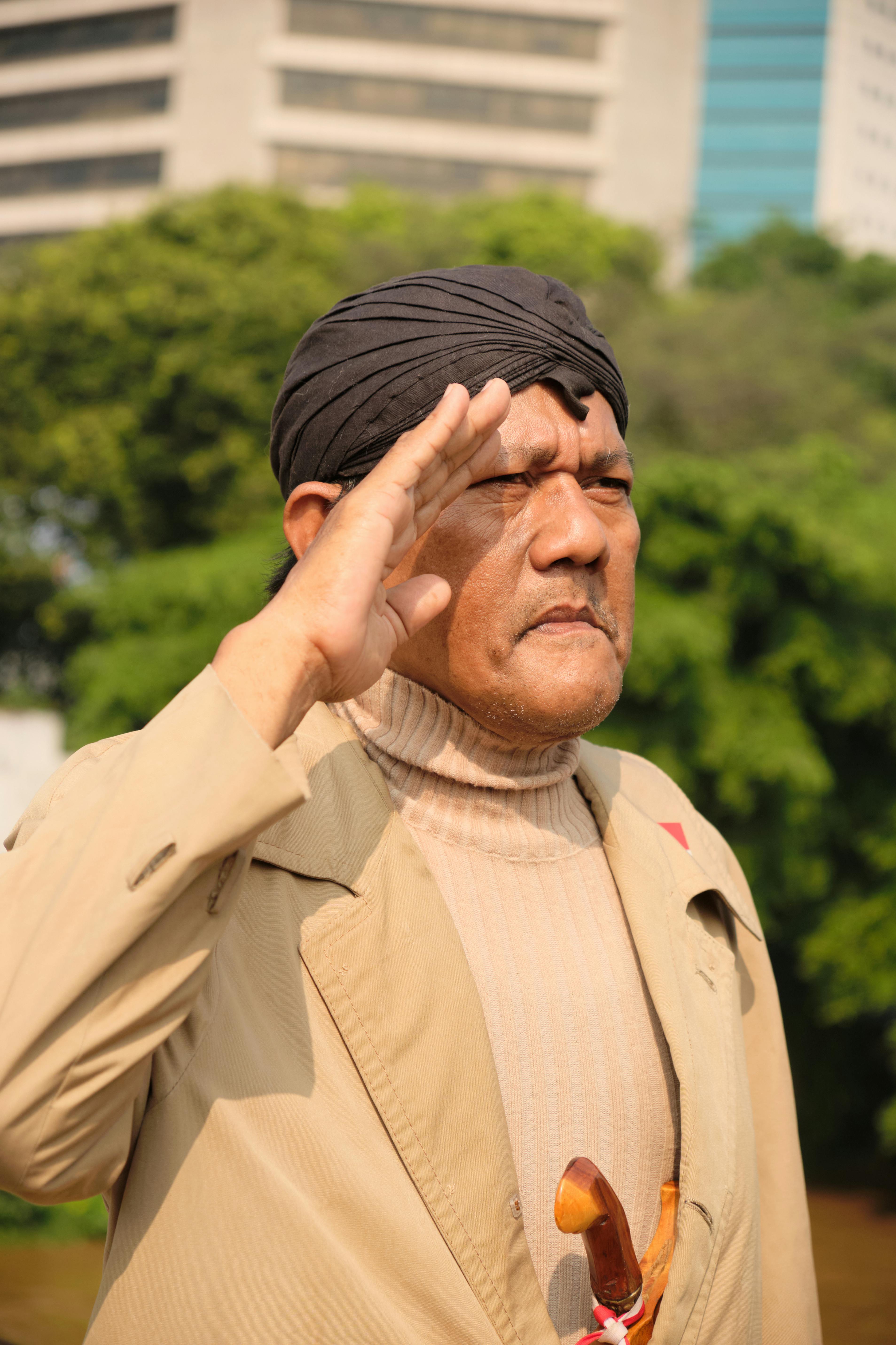 An Indonesian man salutes in a park in Jakarta, showing patriotism and cultural pride.