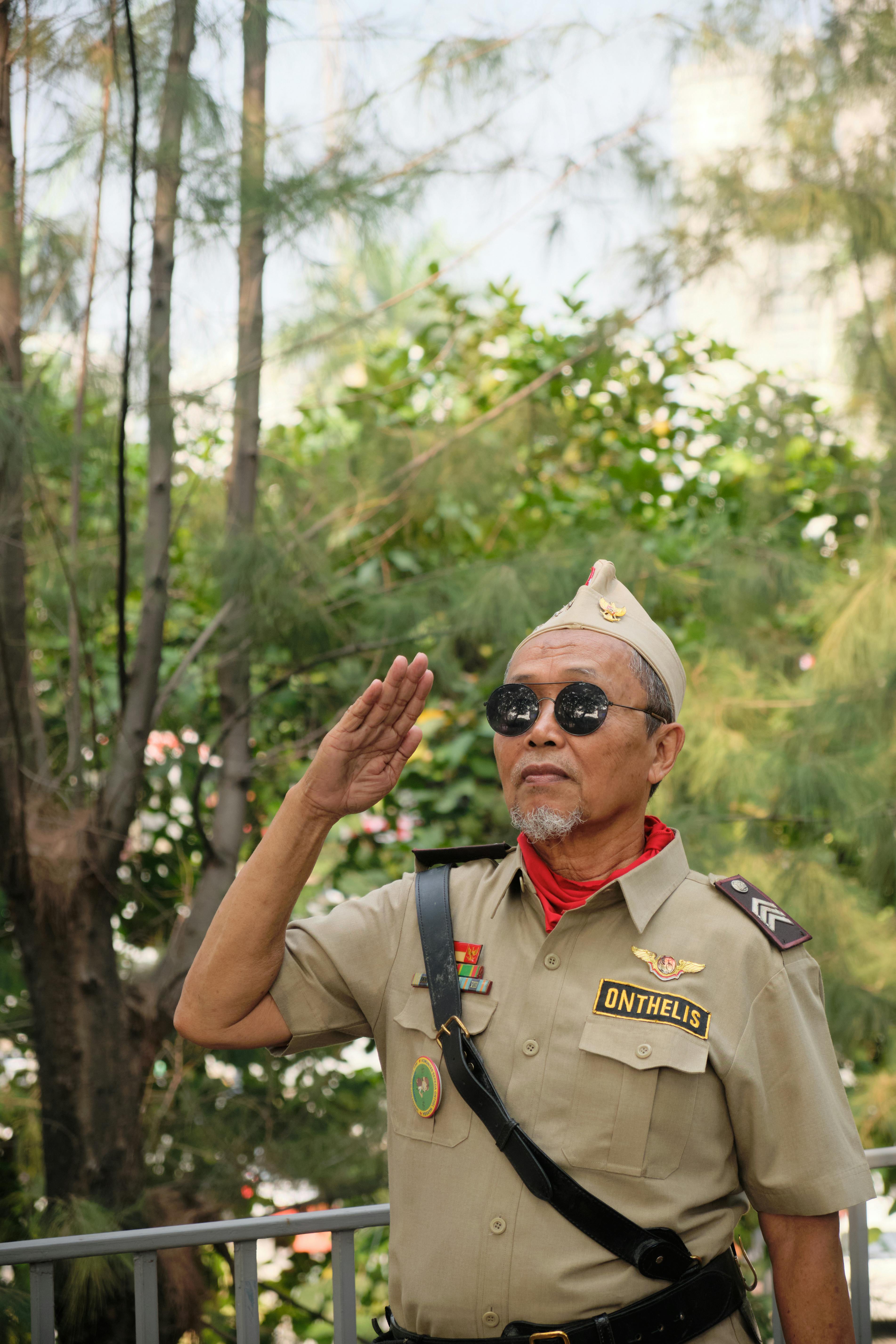 Elderly Indonesian veteran saluting outdoors, symbolizing patriotism and nationalism.