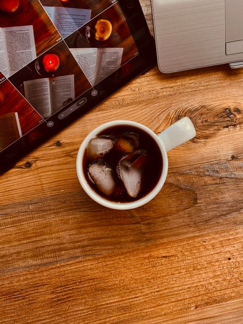 Free Top view of iced coffee beside a tablet on a rustic wooden surface. Stock Photo