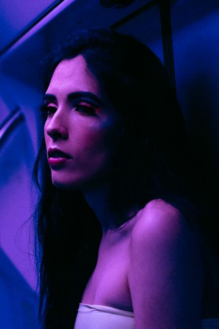 A thoughtful woman in a neon-lit environment creating a dramatic mood.