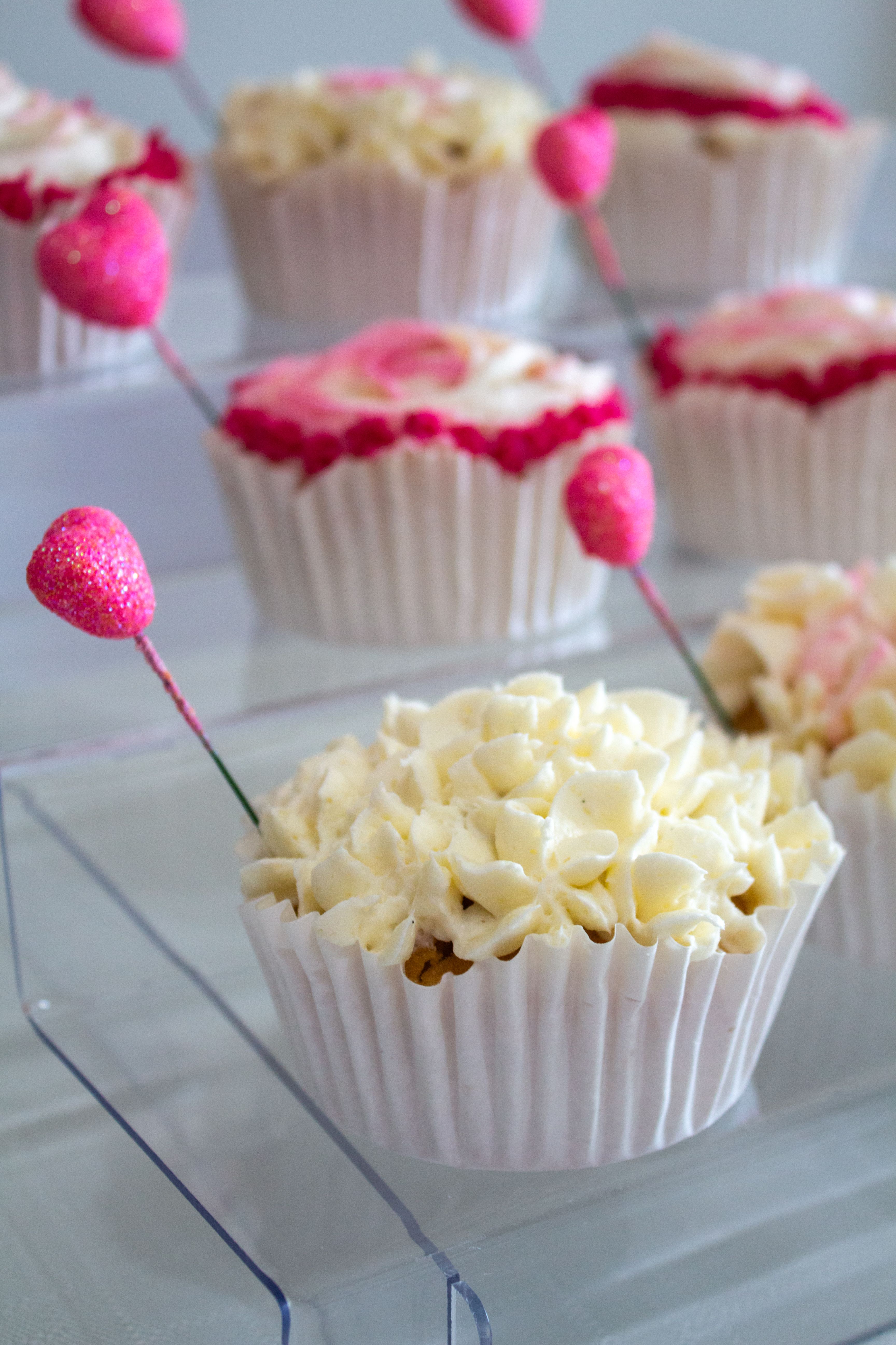 Delicious cupcakes with white frosting and pink heart decorations, perfect for weddings or celebrations.