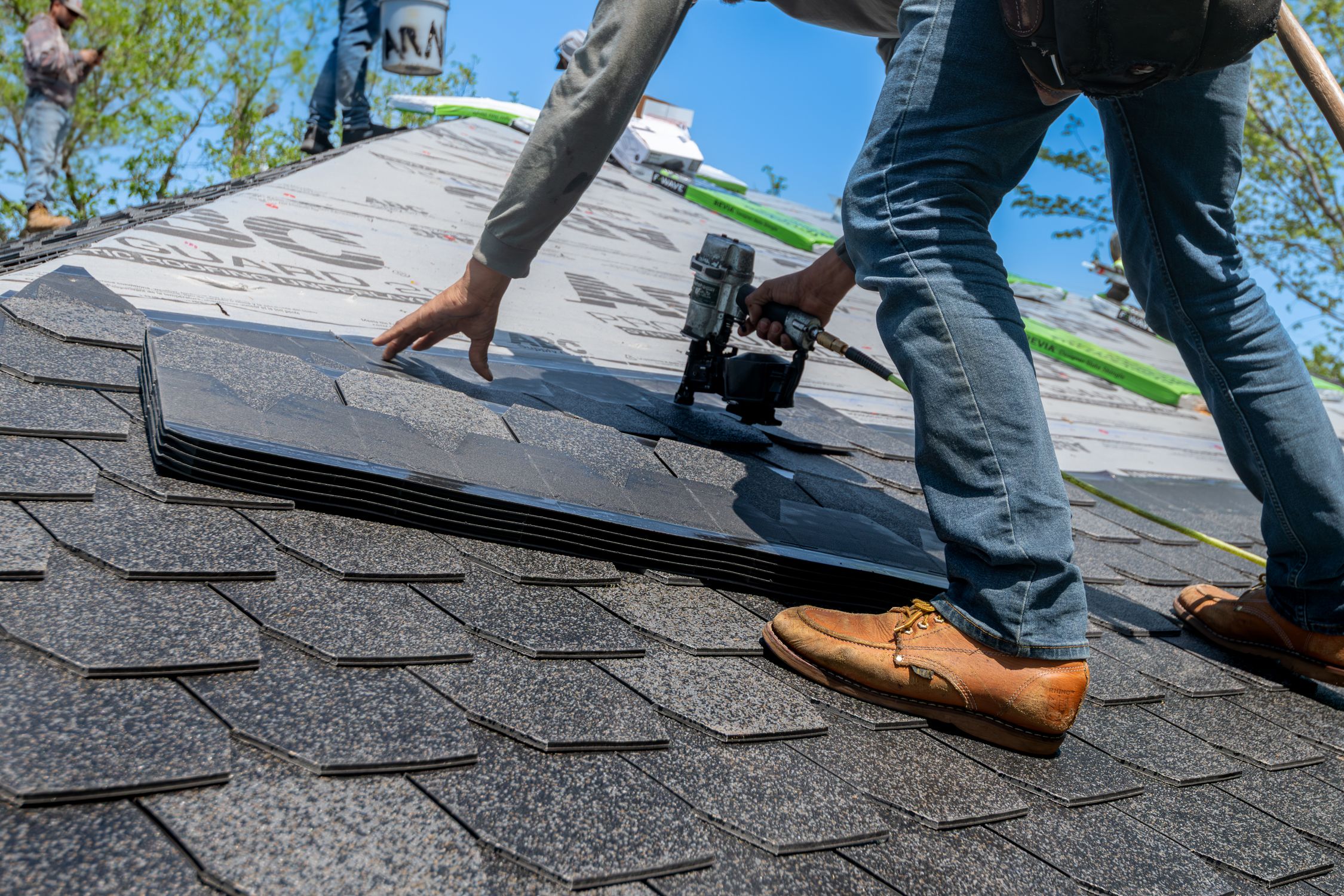Professional roofer installing asphalt shingles on a new residential roof
