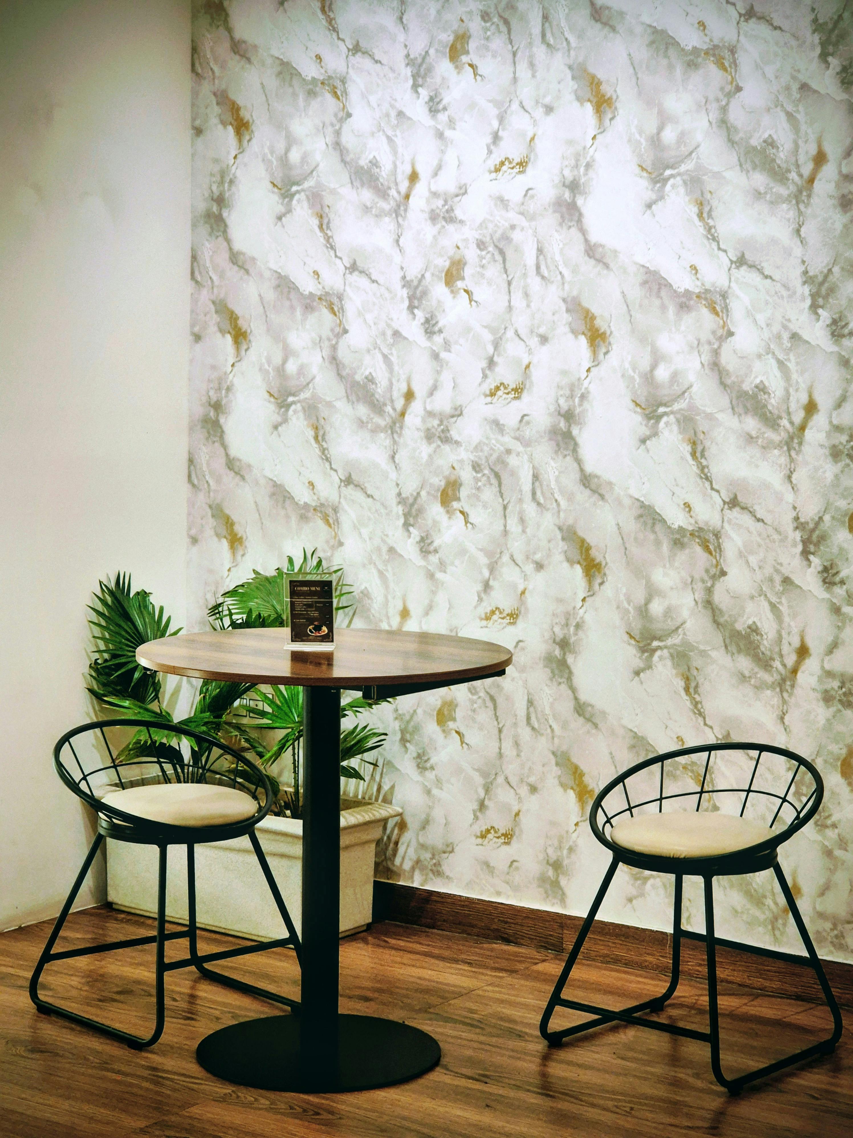 Gratuit O masă elegantă și scaune așezate lângă un perete cu textură de marmură într-o cafenea din Bengaluru. Fotografie de stoc