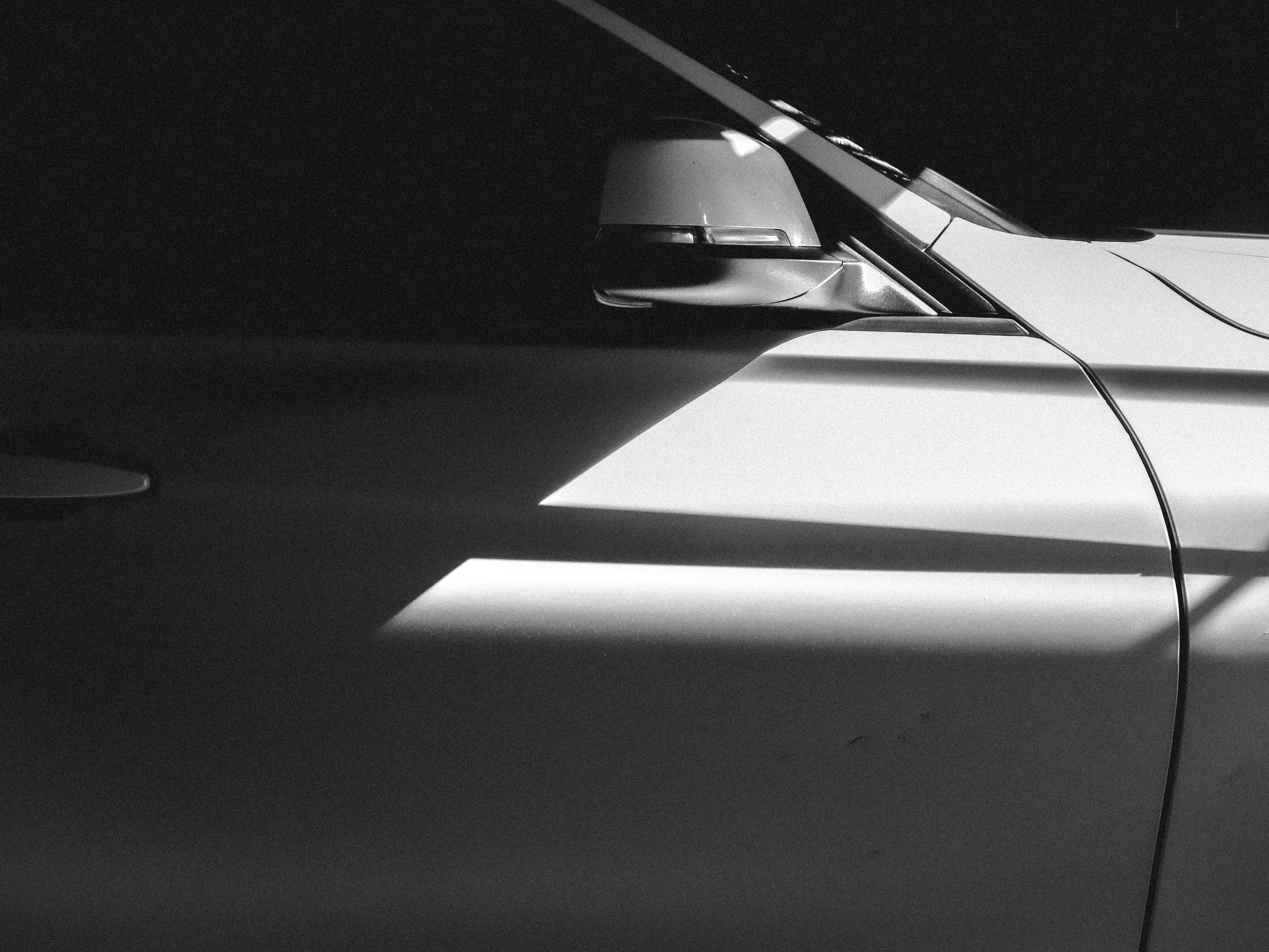 Kostenlos Schwarzweißfoto einer Seitenansicht eines Autos mit Lichtreflexion. Stock-Foto