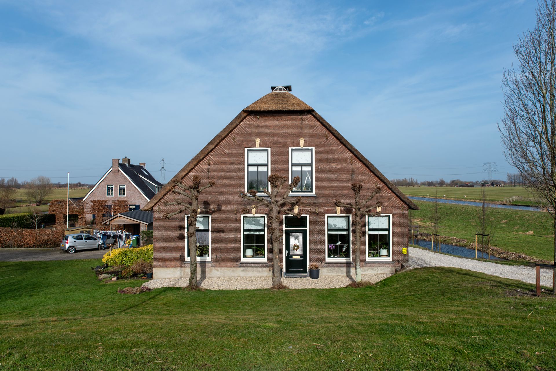 Charming Dutch farmhouse with thatch roof in a scenic rural setting.