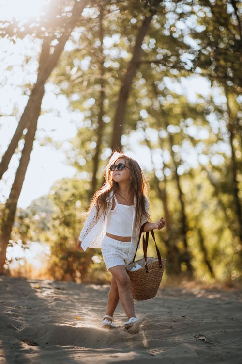 Free Stylish young girl with sunglasses in summer woodland, carrying a woven basket. Stock Photo