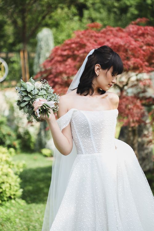 Free Bride in white gown with bouquet in serene garden setting, perfect for wedding themes. Stock Photo
