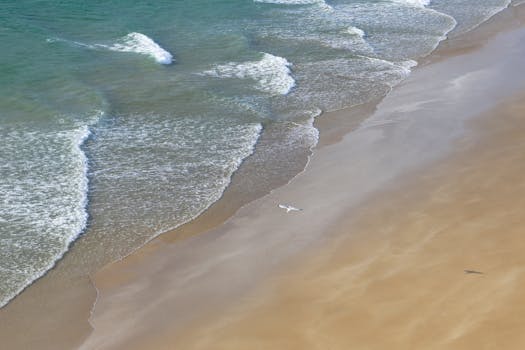 Aerial view of a tranquil beach with gentle waves along the coast of Brittany, France.