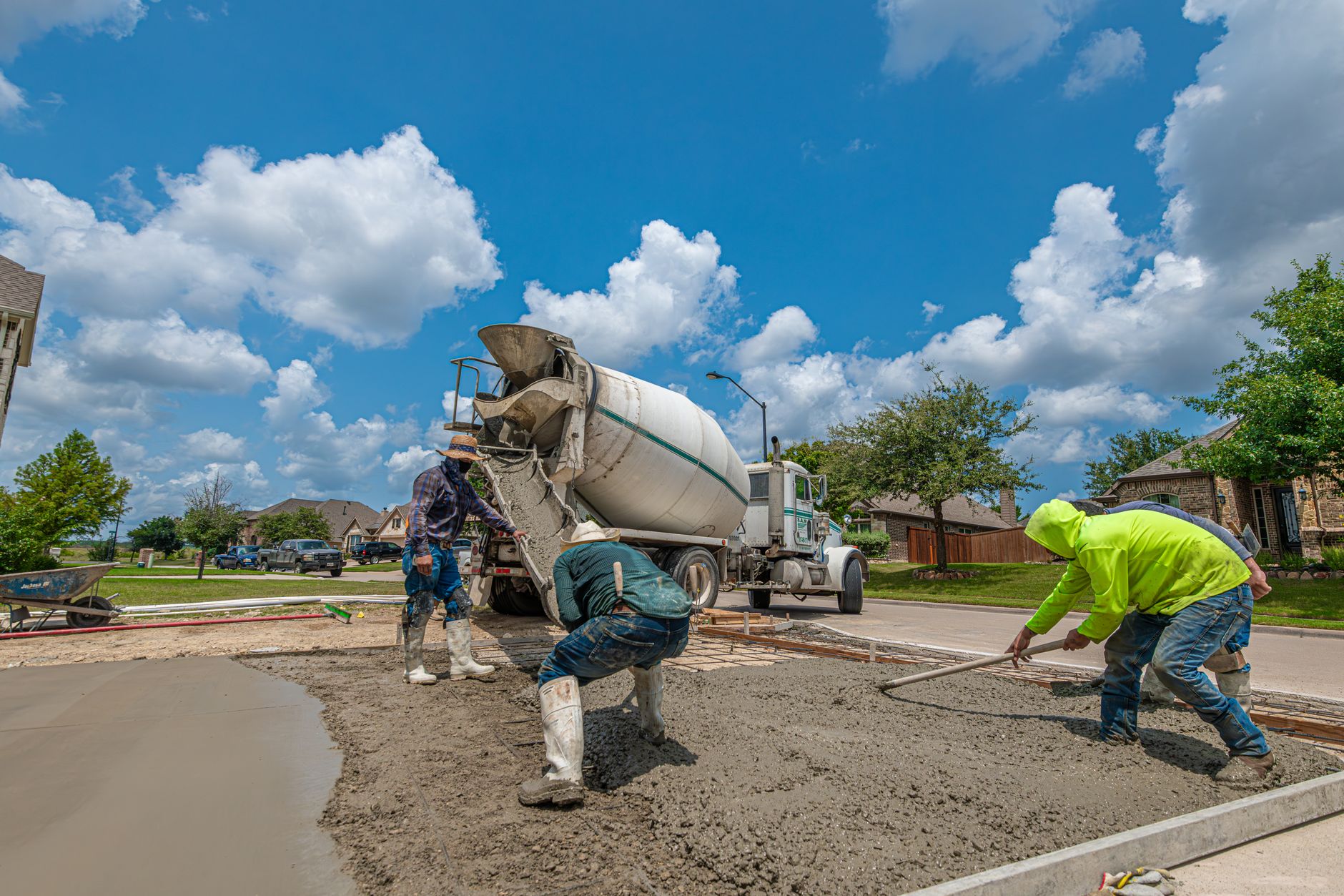 Professional workers laying a concrete driveway in Cambridge under a bright blue sky. Professional workers laying a concrete driveway in Cambridge under a bright blue sky.