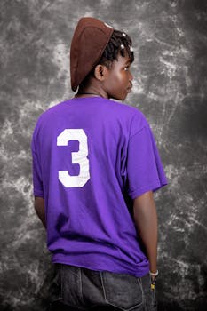 Stylish portrait of a young man in a purple shirt with a number 3, showcasing modern fashion.