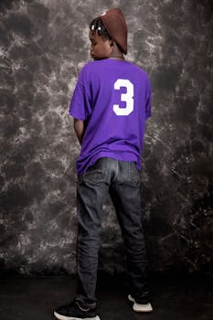 Teenage boy in purple shirt posing against textured background.