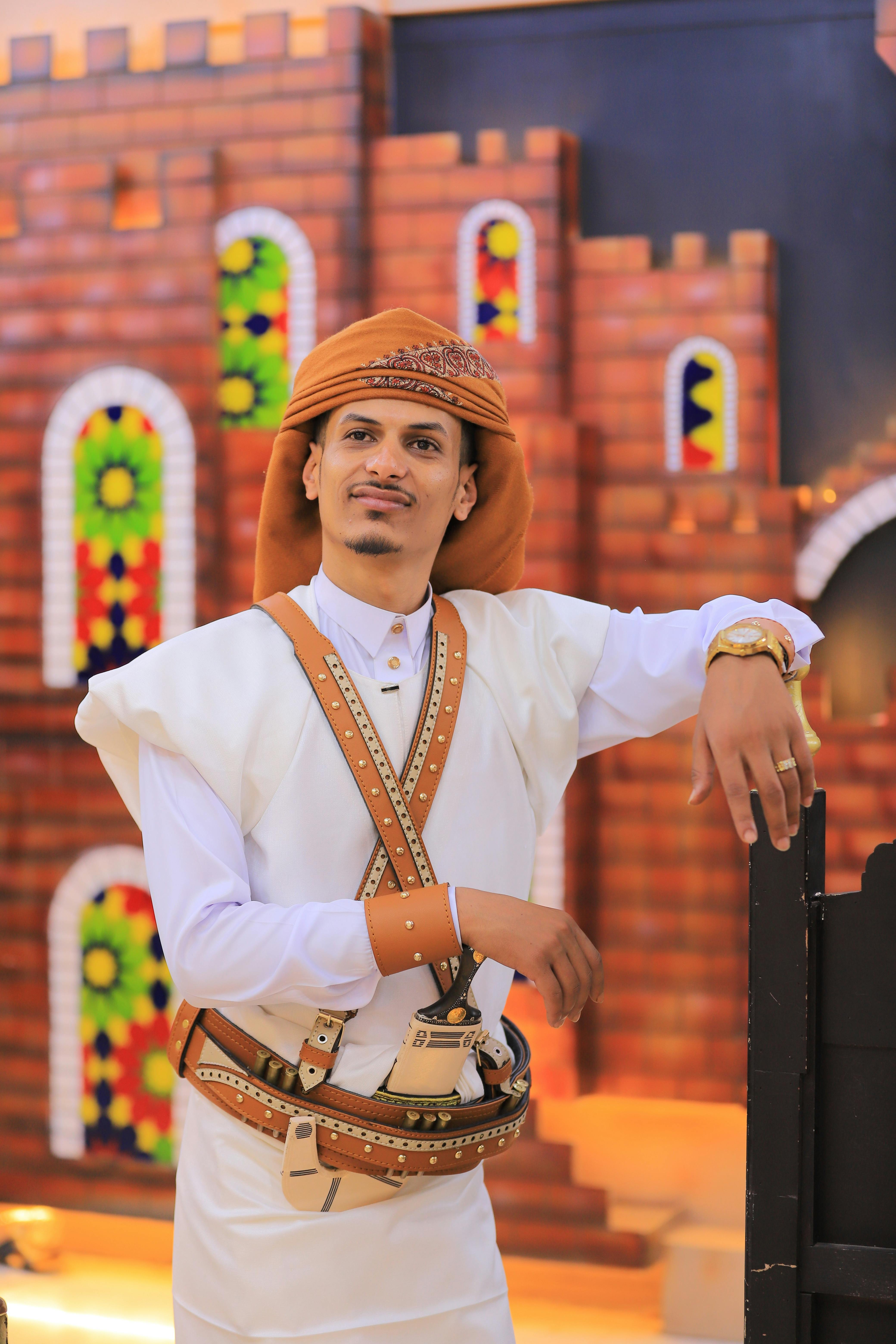 Middle Eastern man in traditional attire standing outside historical building with colorful windows