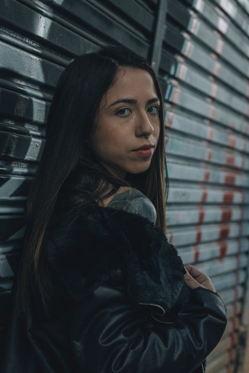 Free A young woman poses confidently in an urban setting with a moody atmosphere. Stock Photo