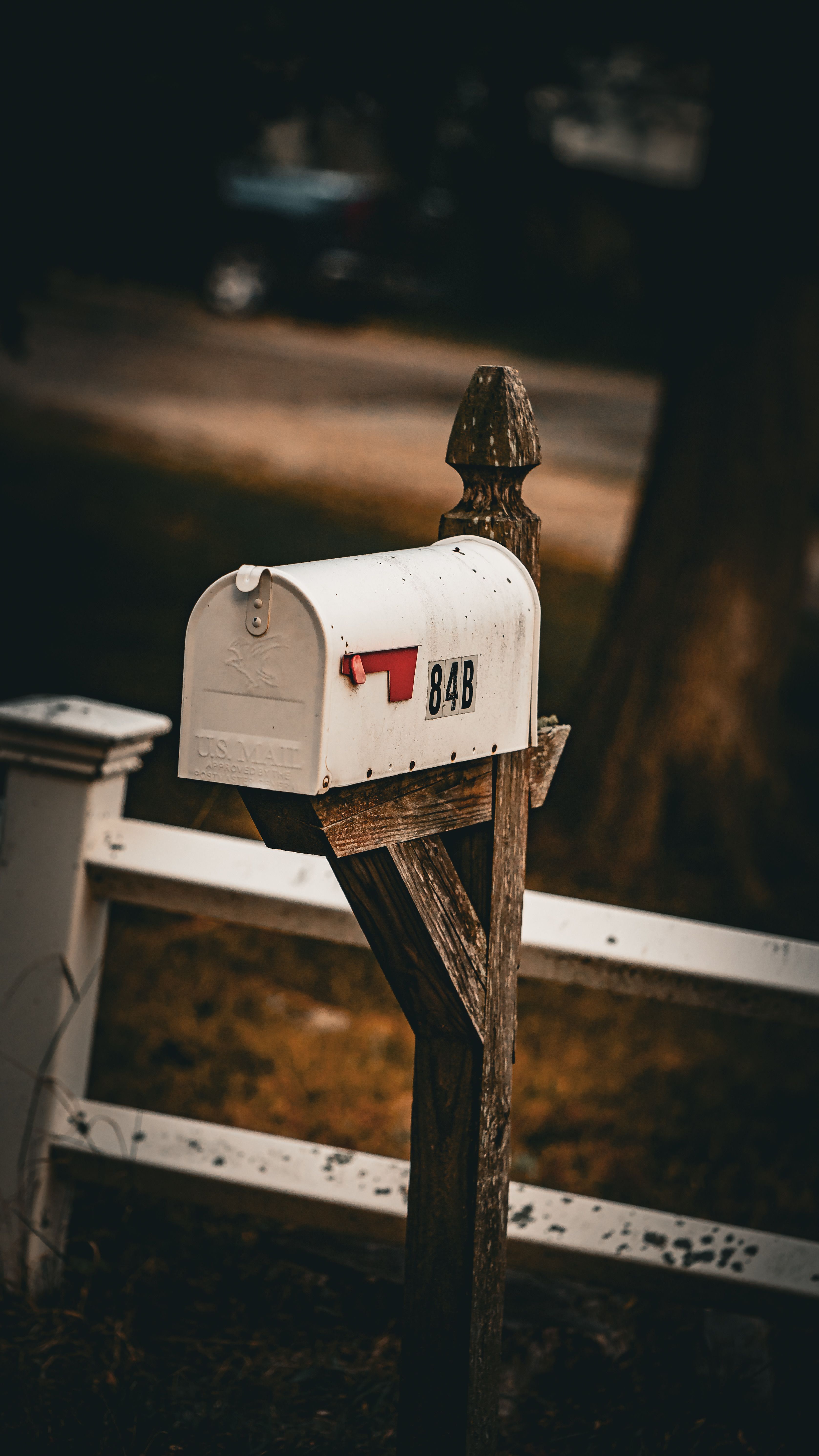 Old-fashioned white mailbox on a wooden post, creating a vintage feel in a rural setting.
