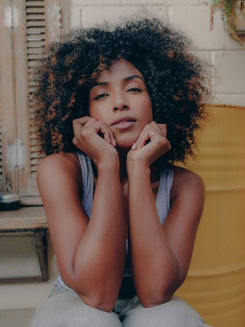 Free Relaxed portrait of a woman with curly hair sitting indoors, exuding calmness. Stock Photo
