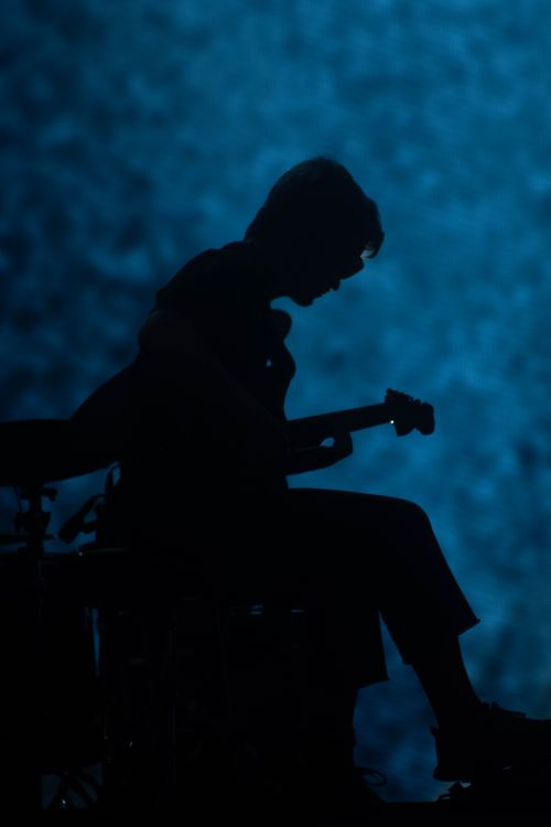 Free Silhouette of a guitarist playing on stage with a dramatic blue background. Stock Photo