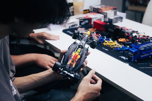 Adults examining a diecast model car collection in Phnom Penh, Cambodia.