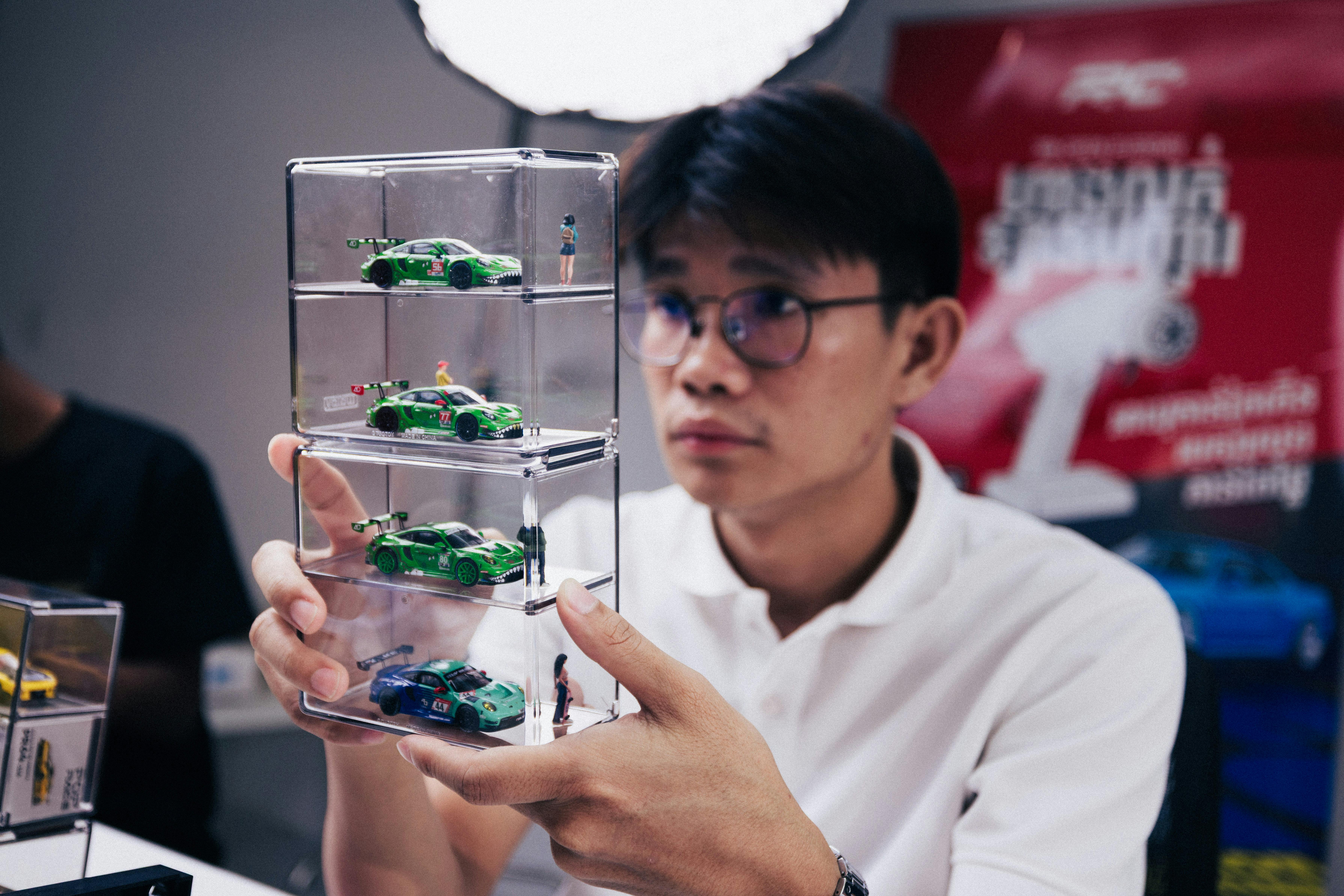 Ücretsiz Phnom Penh'de istiflenebilir bir vitrinde ölçekli model arabaları sergileyen adam. Stok Fotoğraflar