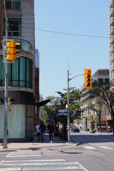 A lively summer day on Toronto's Bloor Street with pedestrians and traffic lights.