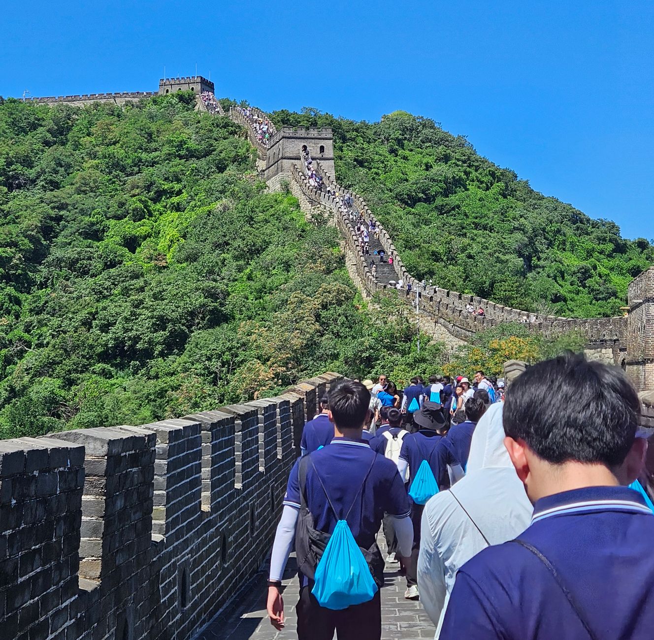 Crowds enjoy a sunny day exploring the historic Great Wall of China.