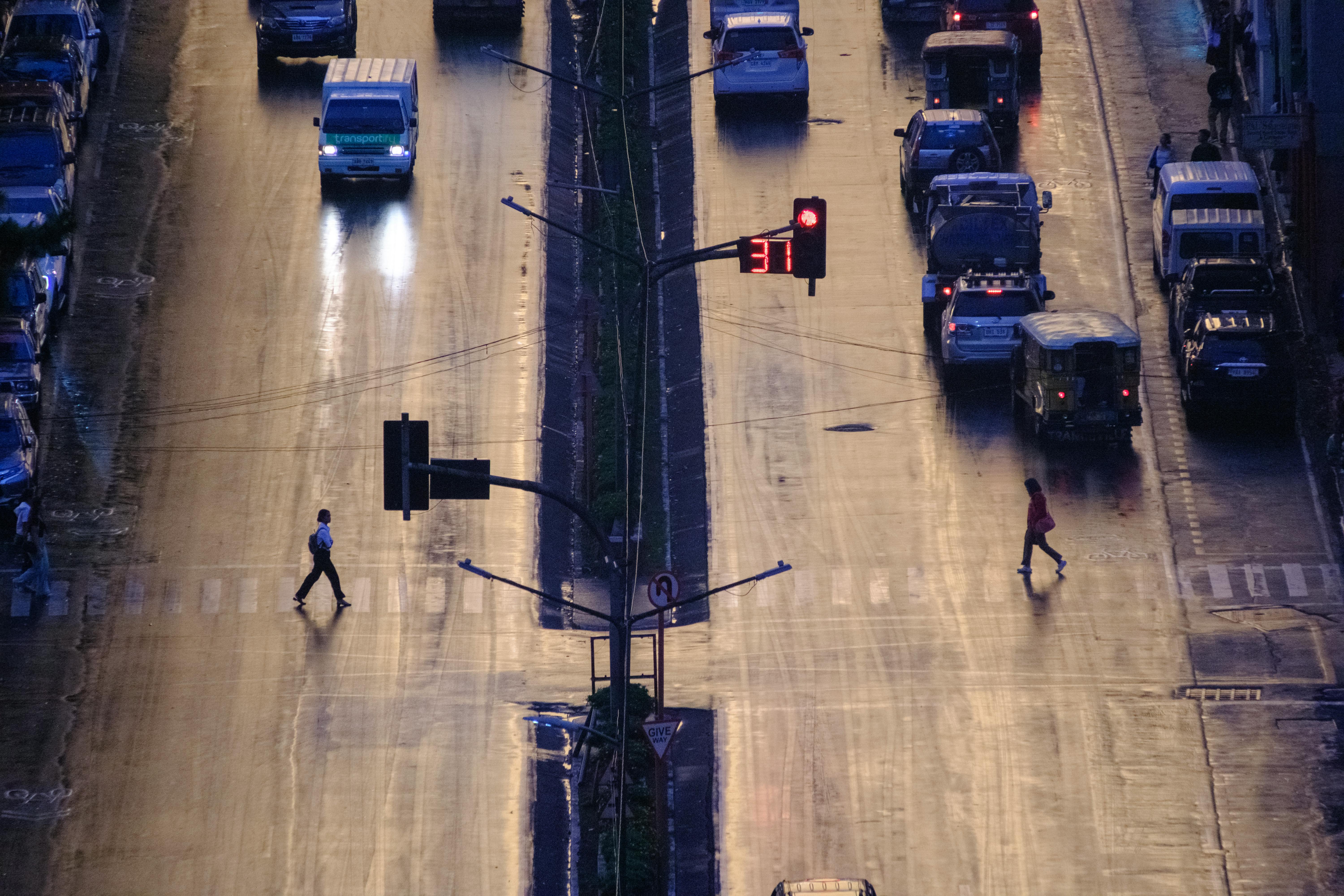 An aerial view of a bustling street in Baguio, Philippines at twilight with pedestrians crossing.