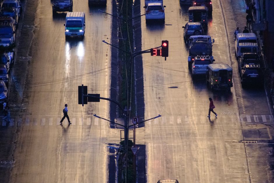 An aerial view of a bustling street in Baguio, Philippines at twilight with pedestrians crossing.