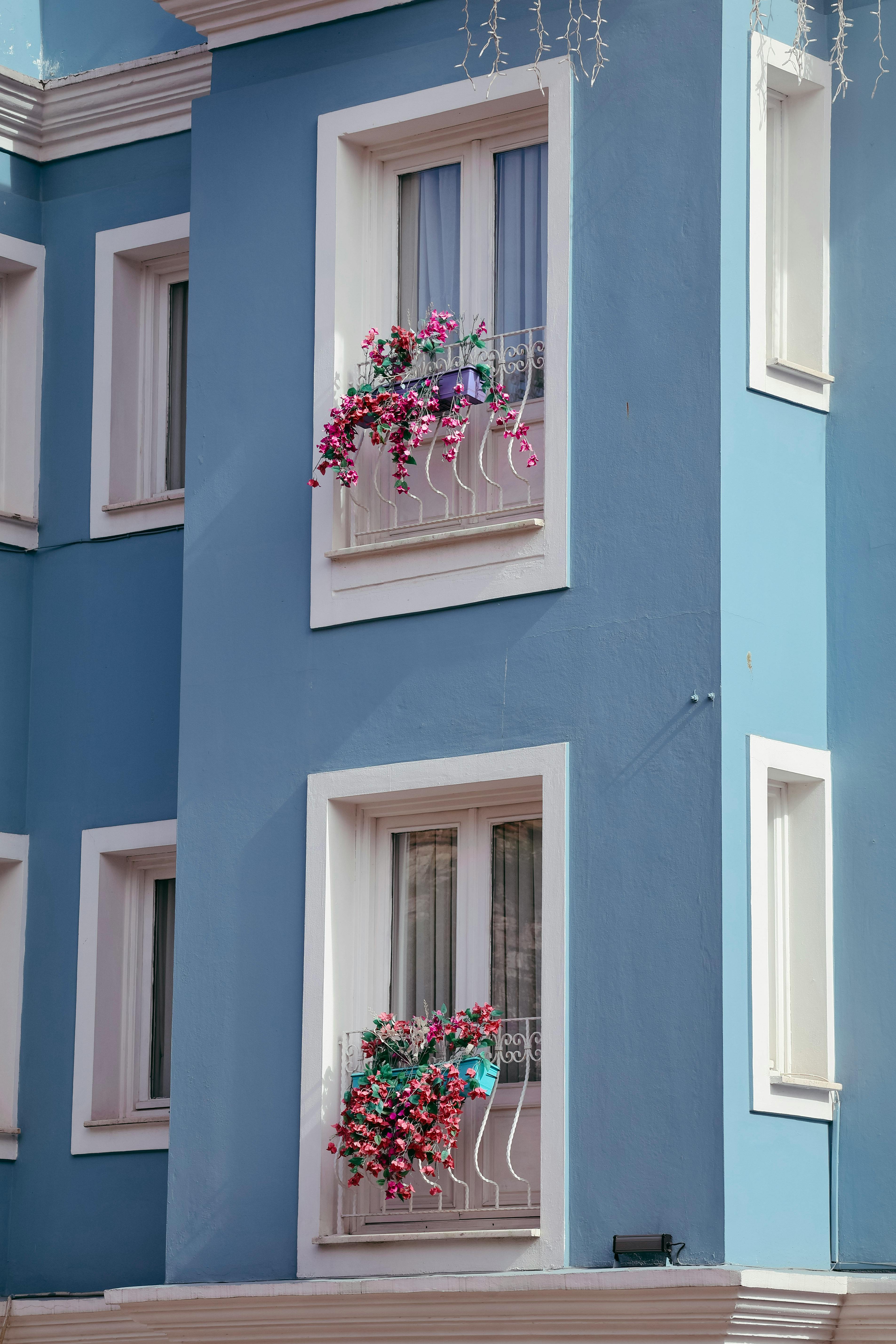 A vibrant blue building facade in Istanbul, adorned with pink floral decorations on the balconies.