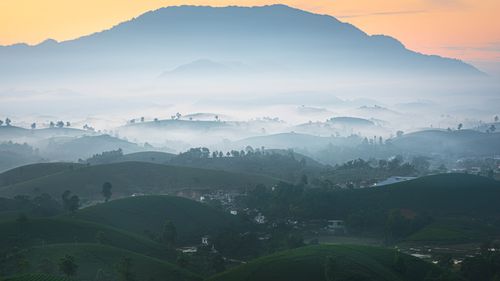 Free A peaceful misty mountain view with rolling hills and sunrise hues. Stock Photo