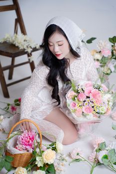 Woman in lace attire arranging beautiful floral bouquet, indoors.