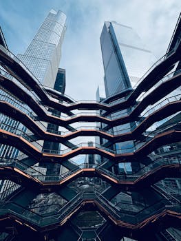 Dynamic view of the Vessel structure at Hudson Yards, NYC against a blue sky.