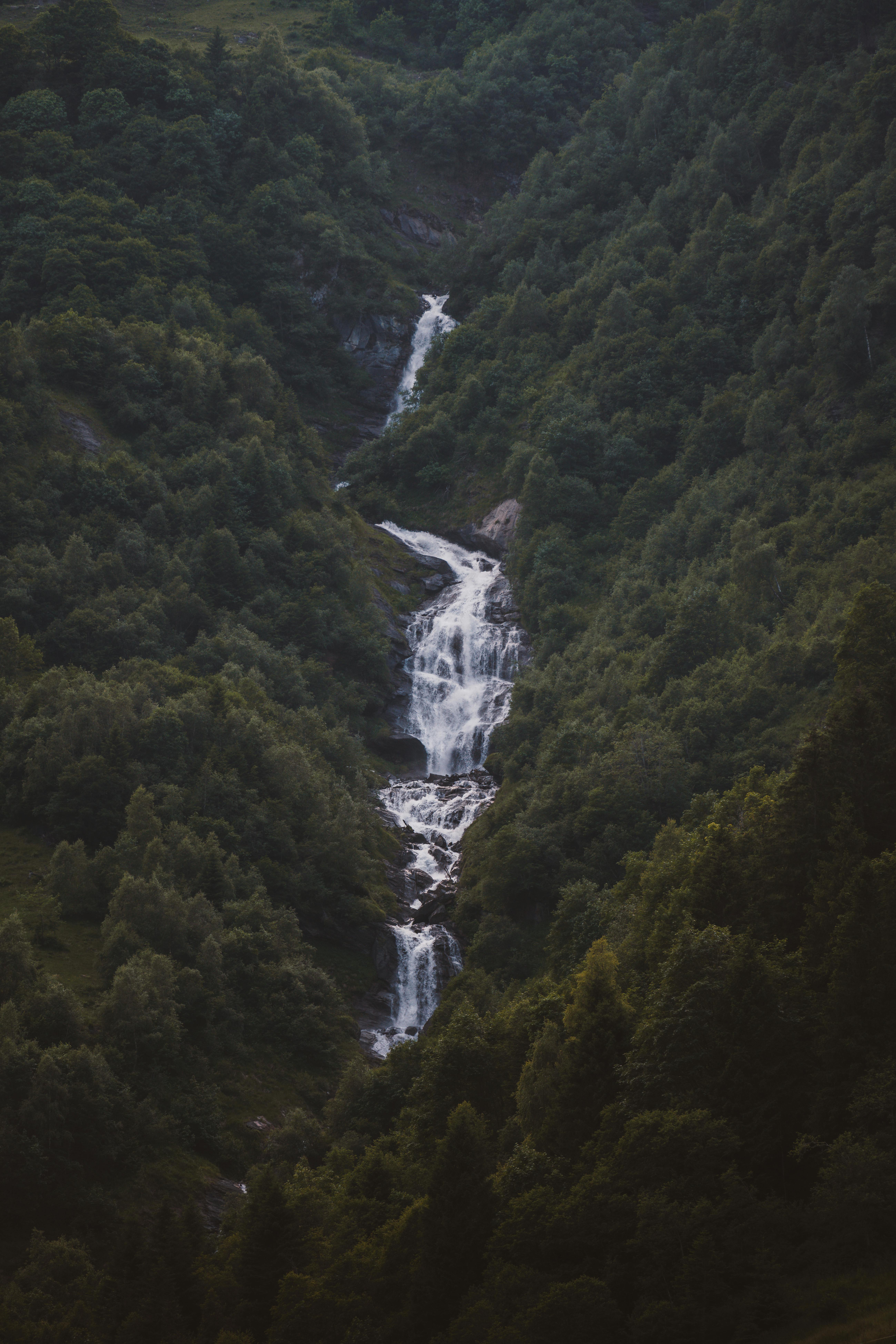 A stunning waterfall cascading down a lush, misty forest hillside, creating a tranquil atmosphere.