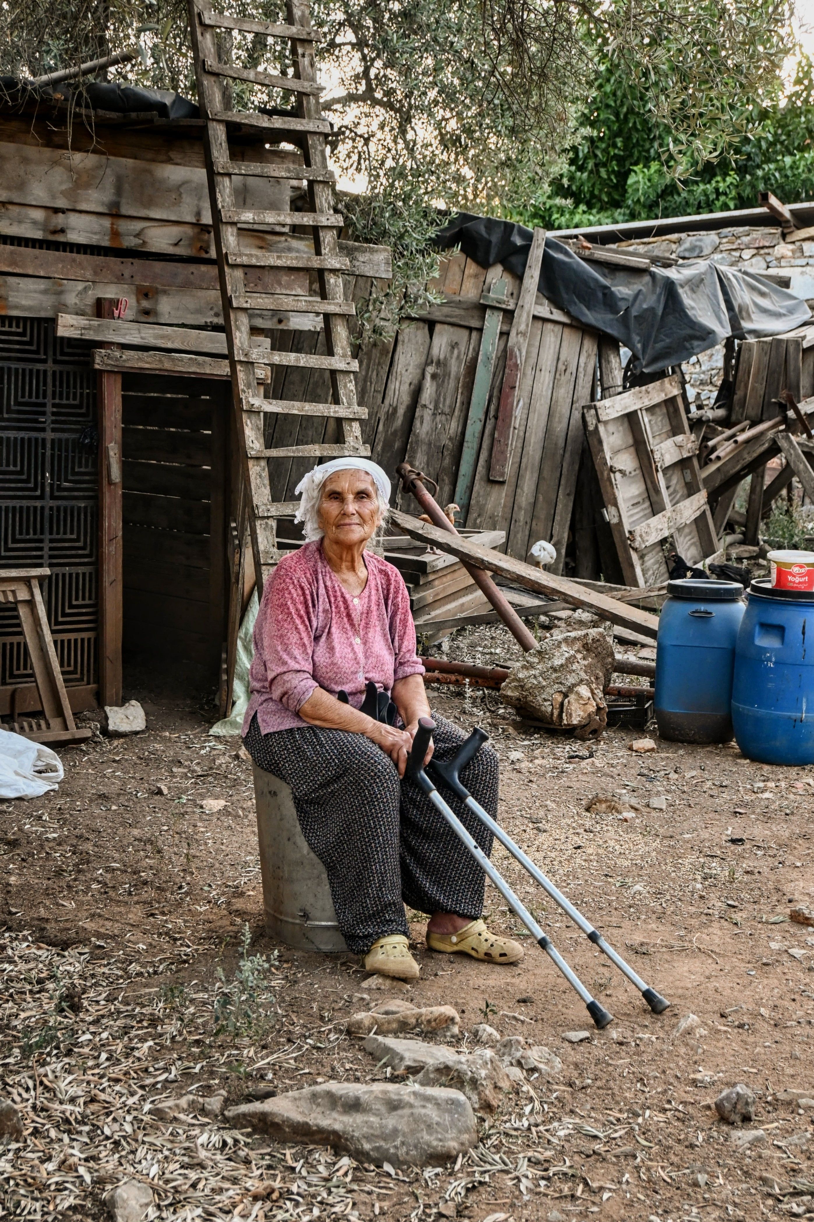 Elderly Woman Sitting Outdoors by Rustic Shed · Free Stock Photo