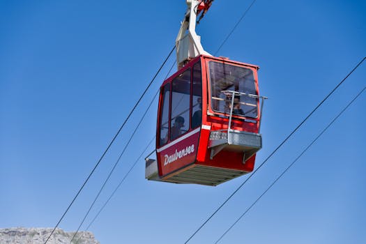 Red cable car traveling over Daubensee in Swiss Alps with clear blue sky.